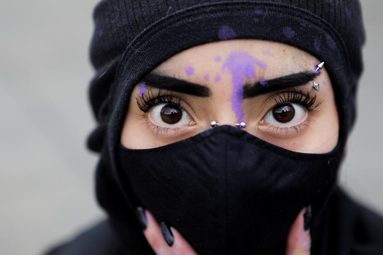 A masked woman poses for a picture during a march demanding justice for the victims of gender violence and femicides in Mexico City, Mexico August 16. REUTERS/Raquel Cunha